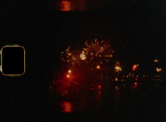 Firework show over an urban lake at night caught on vintage film