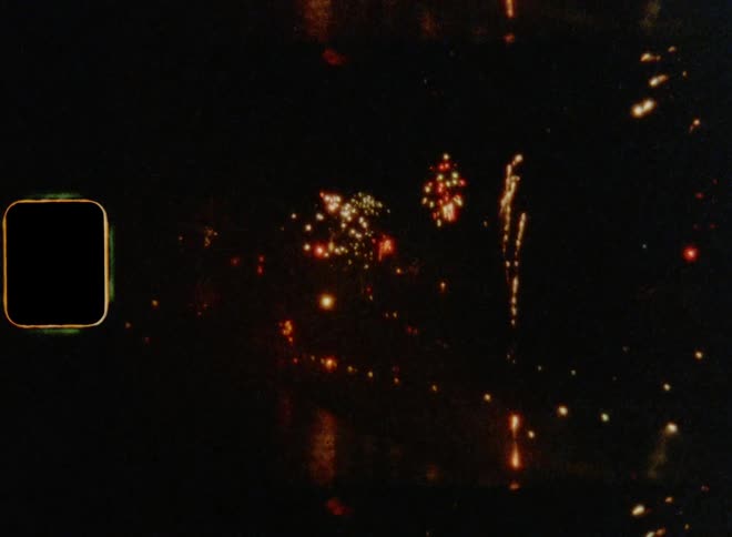 Tilting shot of fireworks flying and exploding in the night sky reflecting on the water