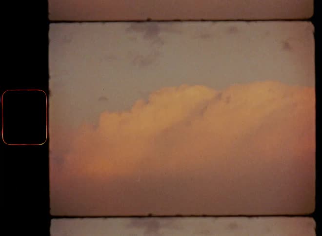 Sunlight reflects on cumulus clouds in a cloudy evening sky with red and orange colours during sunset on vintage film with warm evening tones during golden hour