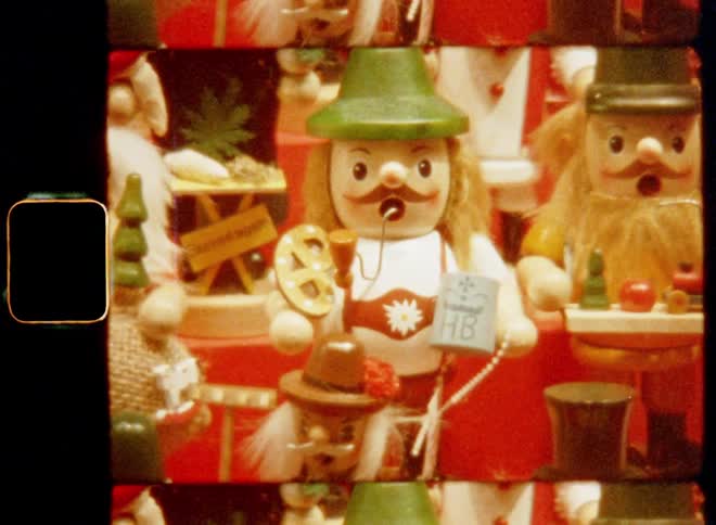 Close up of a display filled with various hand-made wooden Christmas decorations such as an incense smoker and other manikin for sale on an arts and crafts market or fair caught on vintage Super-8mm film