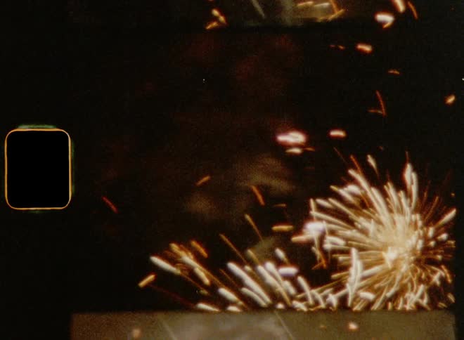 Close up of bright fireworks exploding in the night sky caught on vintage 8mm film