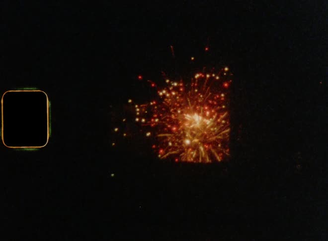 Silhouettes of skyscrapers in front of fireworks spread against darkness glowing golden and red