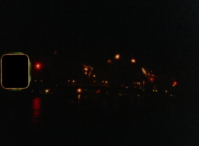 8mm wide shot of fireworks exploding in the night sky over a city
