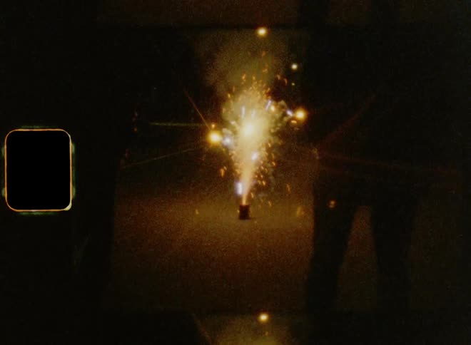 Vintage film stock of two men watching a fireworks sparkler exploding on the ground