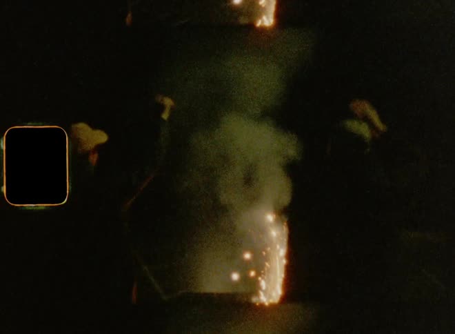 Silhouettes of two friends dancing on the street in front of fireworks celebrating Independence Day on vintage Super 8 mm film