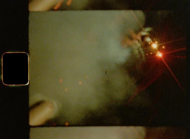 Close up of a hand holding a roman candle shooting bright and colorful light balls into the darkness of the night sky
