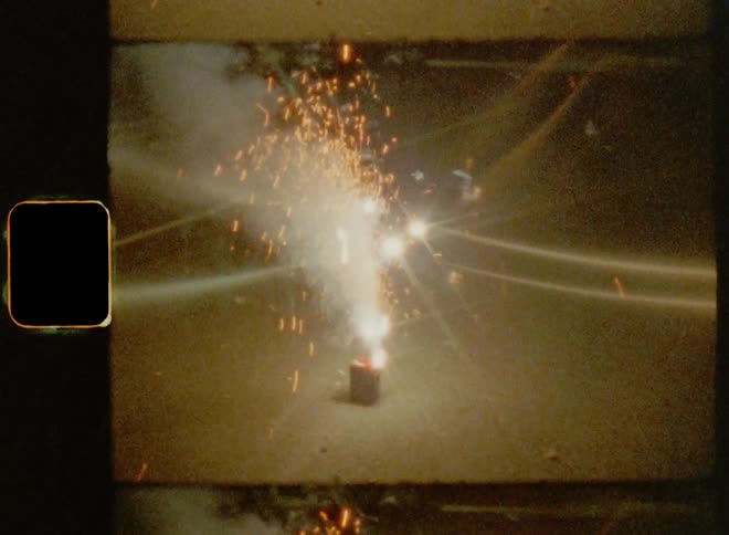 Close up of fireworks exploding on the ground at night caught on vintage film
