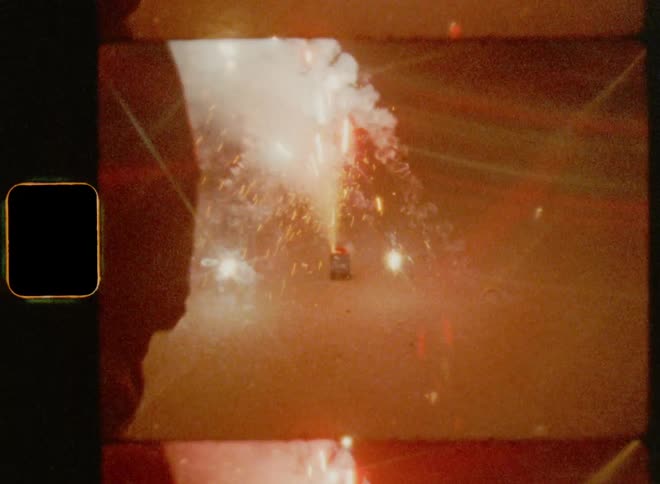 A person is watching colourful fireworks with a lot of sparks and flares outdoors during night while contemplating