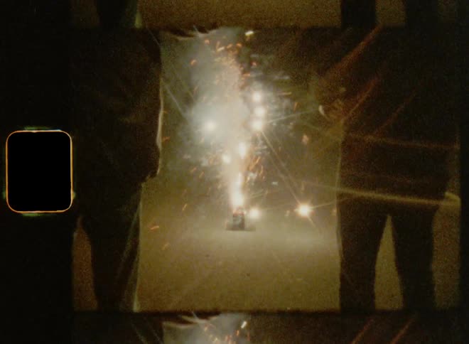 Retro 8mm film of two people celebrating America on July 4th dancing and lighting fire works at night