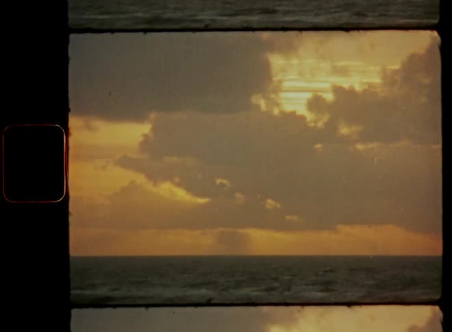 Timelapse of clouds covering the sun on cloudy day with bright glowing sky during a nice evening at the ocean while watching a beautiful sunset at the beach back in the old days