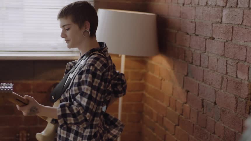 A woman walks over and picks up a guitar