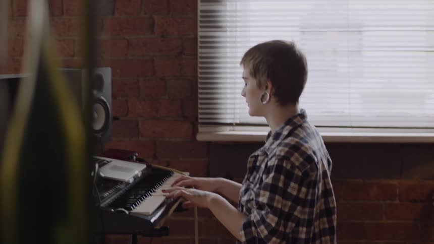 A woman is playing a keyboard in a studio