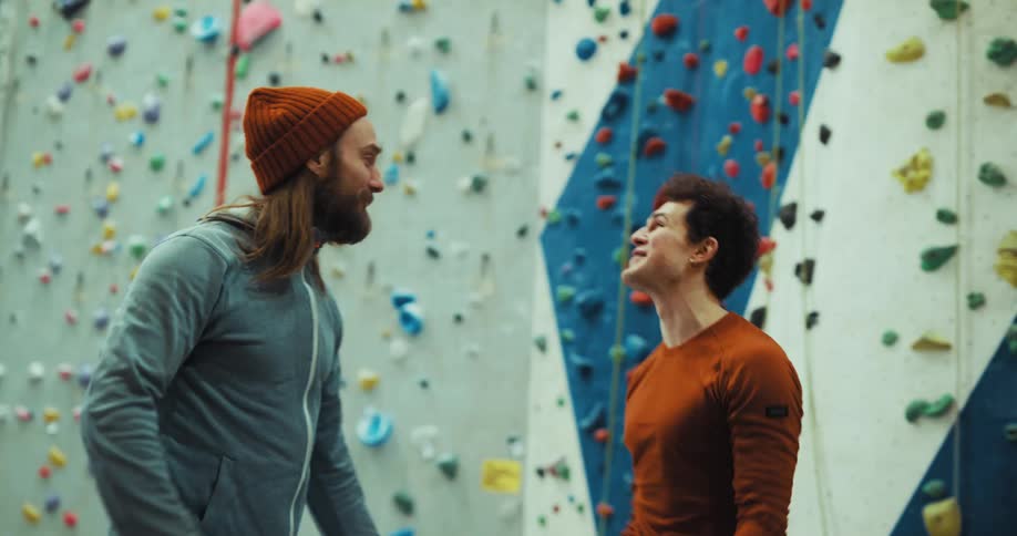 A man jumps rope in front of a rock wall in the gym