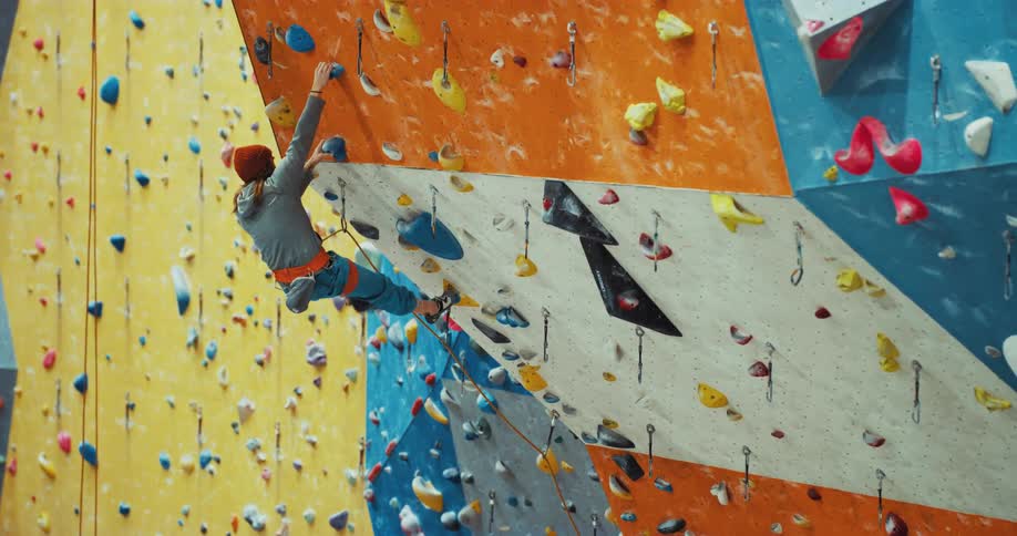 Man wearing harness climbs sloping wall in climbing gym