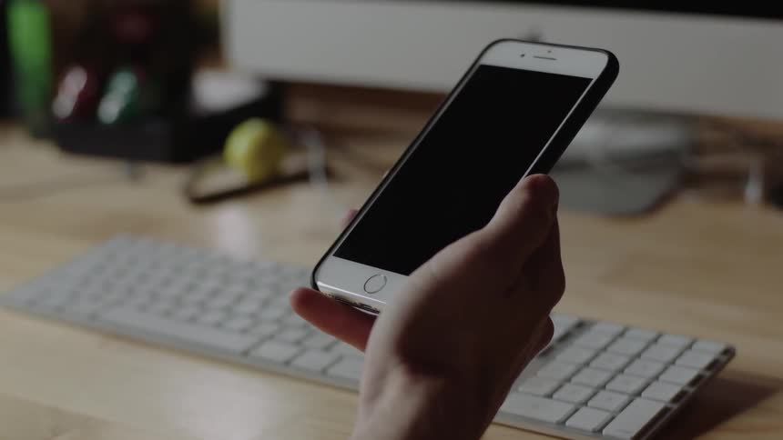 A person is holding their phone by a keyboard
