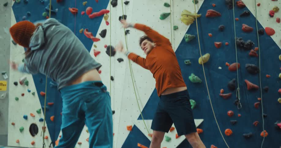 Men exercise and warm up in front of climbing wall