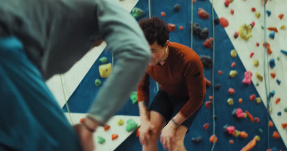 Two men exercise and warm up in front of climbing wall