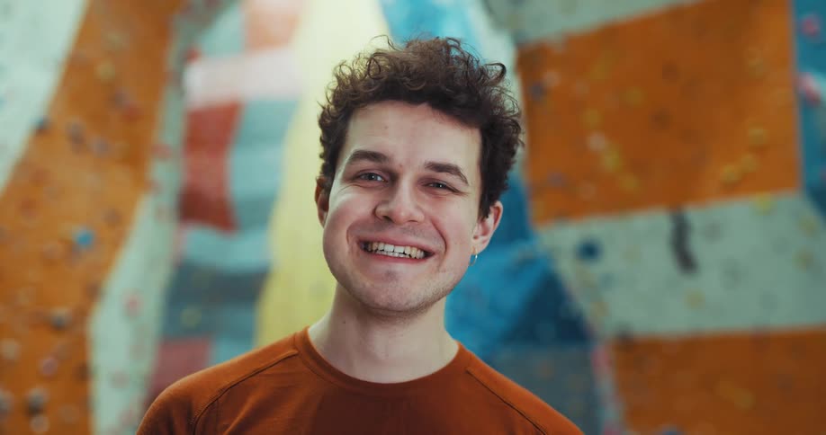Man standing in climbing gym smiles broadly