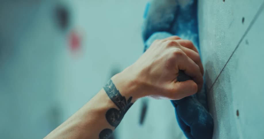 A close up of a man rock climbing on a wall indoors