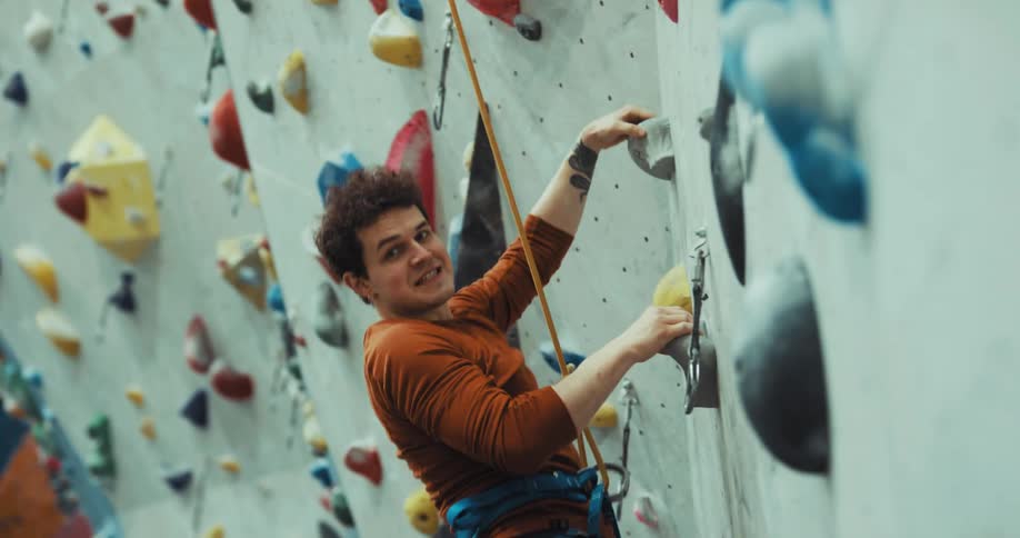 Man climbing the wall with rope tied between his waist