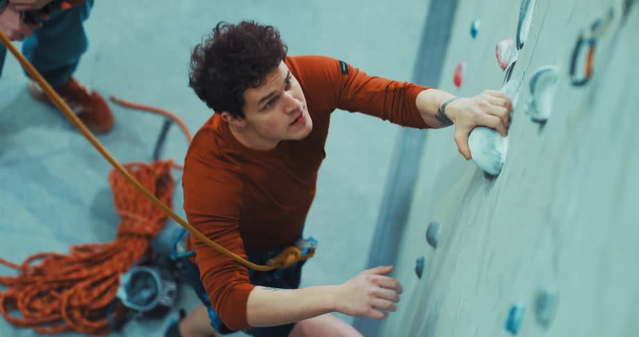 A man prepares to climb up a rock wall in a gym