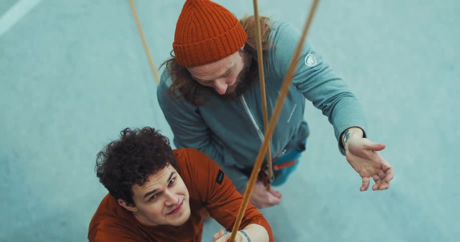 A man explains the rope climbing system to another man in the gym