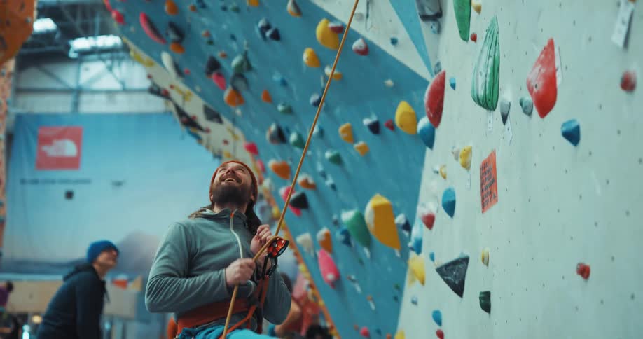 Man trying to climb the art wall through a rope tied on him