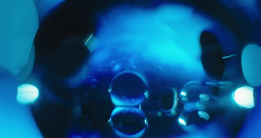 Blue light glows in the distance as the reflection of clear orbs shine in other clear orbs in the shadows