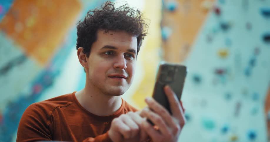 Man in climbing gym scrolls on smartphone