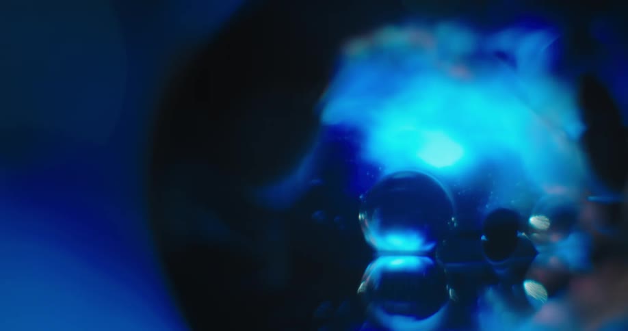 Small spots float around bubbles on surface of blue and black ball against a blue background