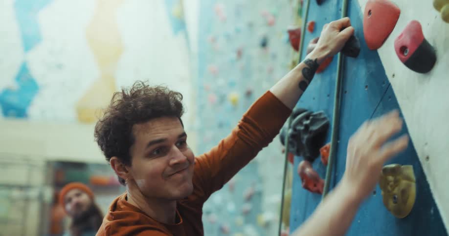 A man climbs up the wall in the gym