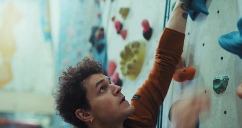 A man tries to climb a rock wall in the gym