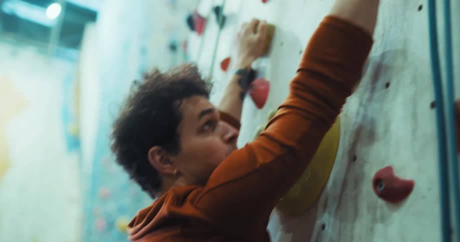 A man climbs up a rock wall in the gym
