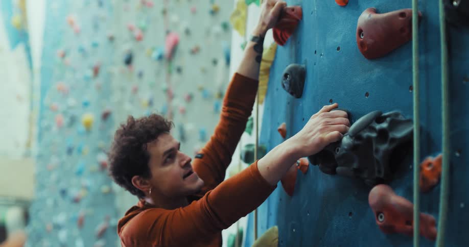 A man starts to climb up an indoor rock wall