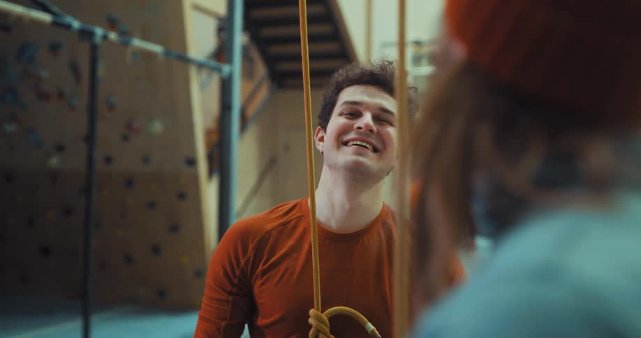 Two men hug after one comes down from climbing an indoor rock wall