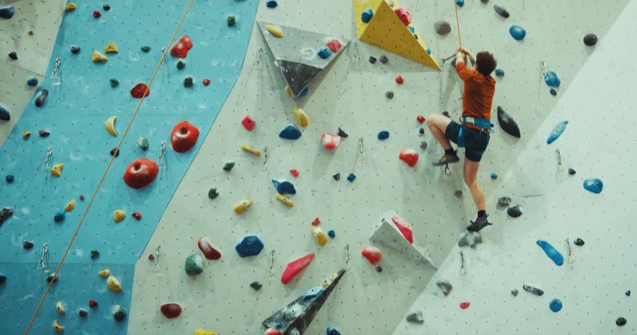 A man climbing a rock wall struggling to grab the next rock