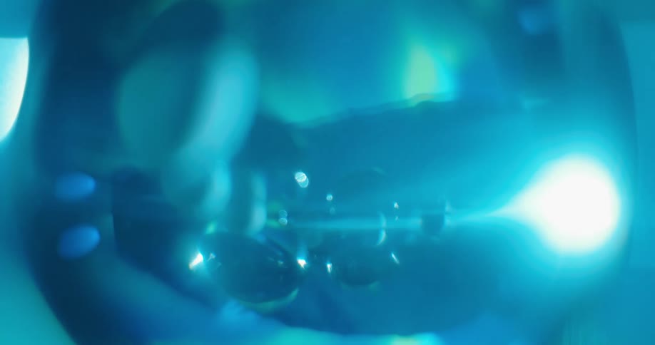 Blue light glows in the distance as the reflection shines in clear orbs as a bright light flares