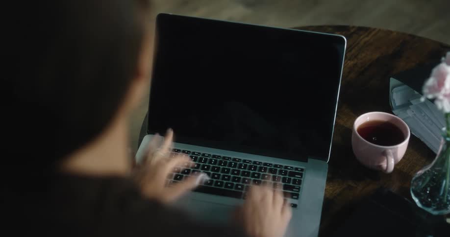 Time lapse of woman with brown coat types on laptop keyboard in room