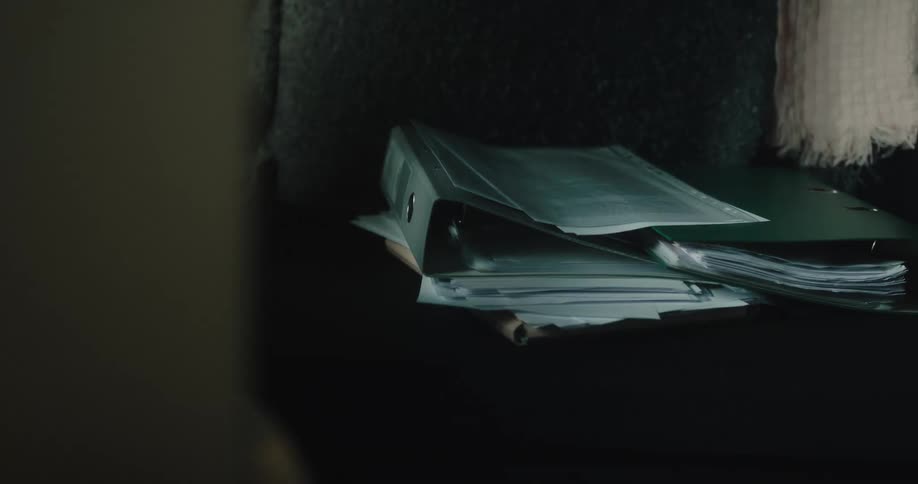 A person stacking papers and binders on a couch