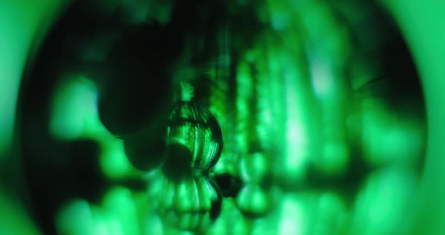 Glowing green lights move inside a black circle as their reflection shines inside small spheres