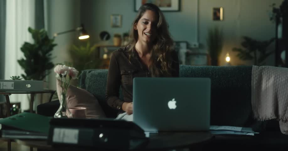 A time lapse shows a woman sitting on her couch working on her laptop