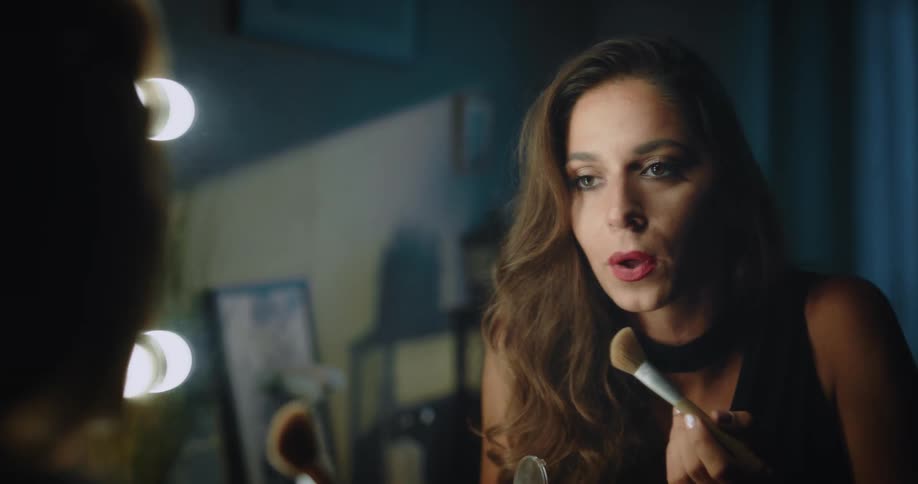 A woman applying makeup with a brush in a mirror