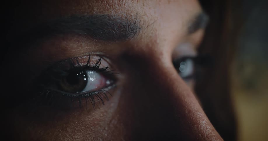 An extreme up close of a womans eyes blinking looking straight head and then to the right