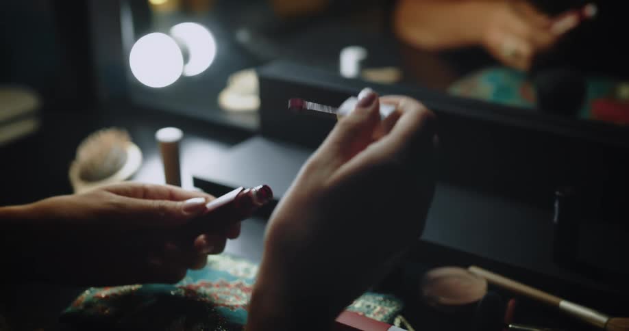 Cosmetics on a desk as a woman opens lipstick and puts it on her lips