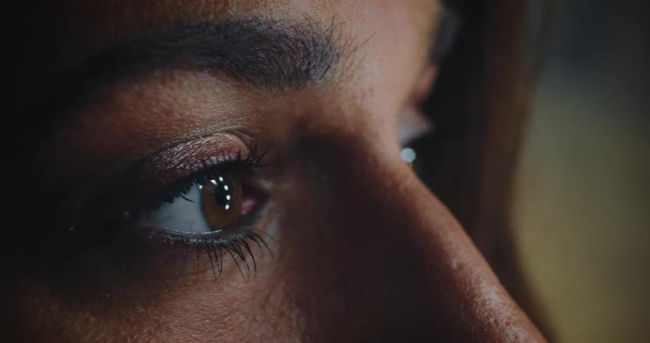 Woman stares ahead as she applies mascara with a mascara brush