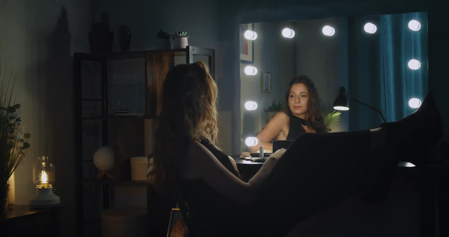 Woman posing in a vanity mirror playing with her hair and smiling