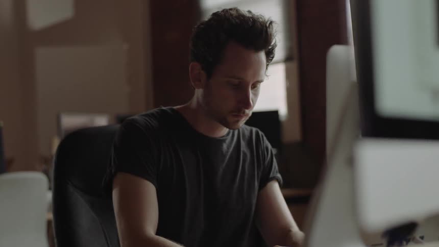 A man puts down a controller and types on a keyboard at a desk