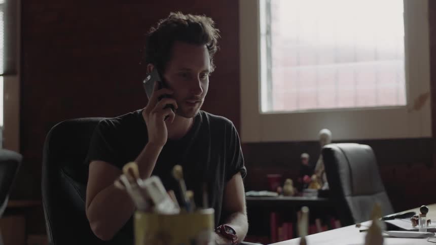 A man sitting at a desk making a phone call