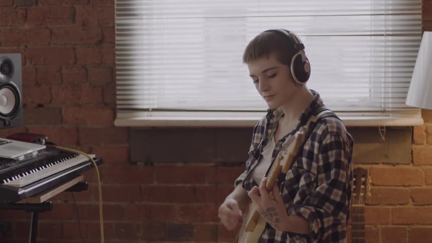 Teenager playing guitar while wearing headphones
