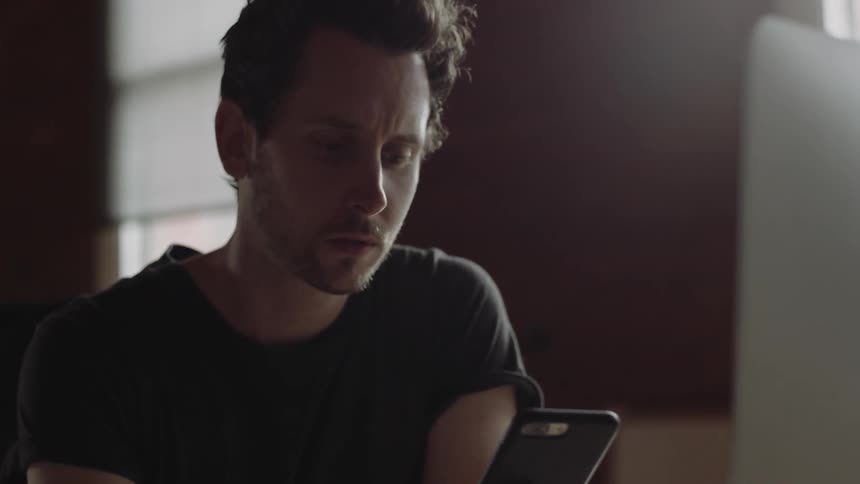 A man holds his chin and looks at his phone